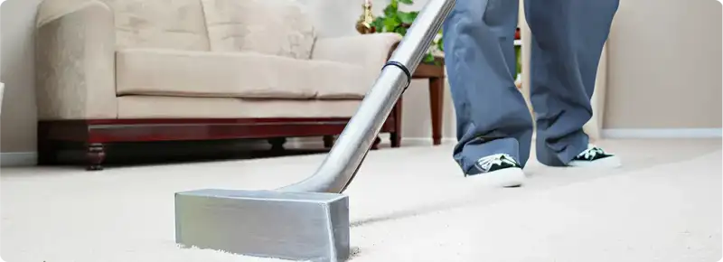 Carpet cleaning technician using a hot-water extraction wand on a light-colored carpet in a living room, Orange, CA.