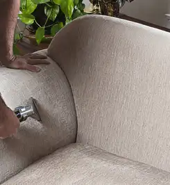 Professional upholstery cleaner deep-cleaning a fabric sofa with a handheld extraction tool and hose Orange, CA.